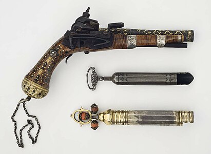 Pistol with its handle and barrel decorated with silver and gold patterns, shown with accessories