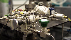 shiny tank and valves and thin pipes and tubes on a desk corner in a lab