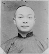 The slightly battered black and white photograph depicts Wong Kim Ark facing directly towards the camera. He has a round face, short receding hair and is wearing a jacket with a standing collar and rounded edges