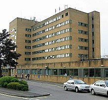 Modern building with 7 floors of windows. In the foreground is a road with cars.