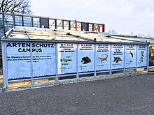 Außenaufnahme des Artenschutzcampus im Allwetterzoo Münster. Glasbau mit Informationsfolien beklebt.