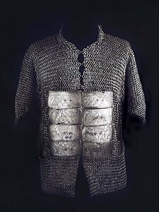 Shirt for a human torso, made of interlinked metal rings, with eight engraved metal plates on the belly area