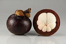 Photograph of a whole mangosteen fruit, and one partially peeled to show the horizontal cross-section which reveals the white internal flesh divided into seven sections.