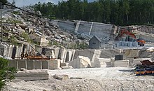 Foto eines Steinbruchs, in dem unter anderem ein Bagger steht