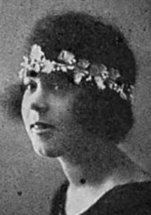 A young black woman with natural hair, wearing a laurel-shaped headband