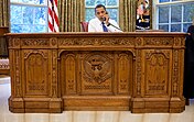 Barack Obama seated at the Resolute desk