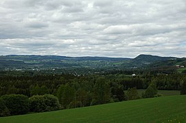 Foto einer teils bewaldeten hügligen Landschaft