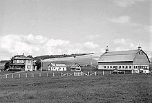 A black-and-white photo of a farm in a valley