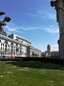 Photo of grand building, blue sky with a few clouds and bright green grass.