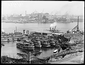 Sydney Ferries Limited base at Milsons Point with early Sydney Harbour Bridge construction underway at opposite Dawes Point