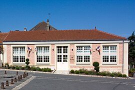 Vue d'un bâtiment bas à la façade rose et aux grandes baies à petits carreaux.