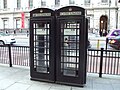 Two black K6 telephone boxes in Piccadilly in the City of Westminster, operated by New World Payphones Ltd