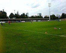 Photographie d'une pelouse verte, avec quelques joueurs en plein entraînement.