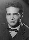 young short-haired man in formal jacket and a bow tie looking into the camera