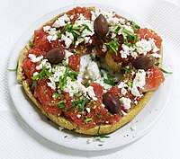 Dakos, traditional Cretan appetizer. Paximadi (hard bread) topped with fresh tomato, fetta cheese, oregano and olives drizzled with olive oil.