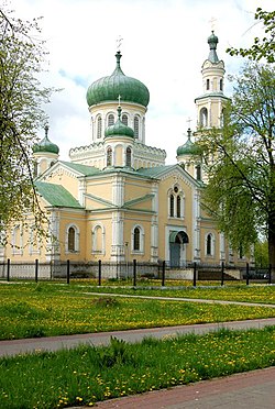 A yellow church with green domes