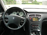 Dashboard of car with analogue gauges, driver's airbag, compact-cassette head unit, and a colour satellite navigation screen