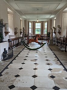 A Tudor long gallery, with stone floors, wooden furniture and bust sculpture