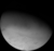 A large spherical object is half-illuminated from the bottom-left. The south pole faces to the light source. Around it in the bottom-left part of the body there is a large white area with a few dozens dark streaks elongated in the pole to equator direction. This polar cap has a slight red tinge. The equatorial region is darker with a tint of cyan. Its surface is rough with a number of craters and intersecting lineaments.