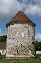 Bâtiment cylindrique en moellons, couvert d'un toit conique en tuiles plates et surmonté d'un épi de faîtage métallique