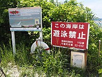 海岸入口の看板とAED。右側の看板は、赤色の「遊泳禁止」と黄色の「遊泳注意」（遊泳可能時）に差し替えられる。