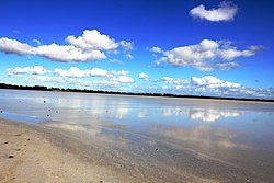 The photo shows Lake Beeac and the sky above it. The surface of the water is mirror-like, it reflects the blue sky and the clouds in it.