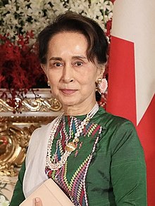 Aung San Suu Kyi standing before a microphone