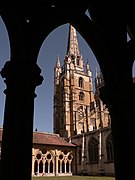 Vue d’une flèche d’un édifice religieux depuis une ouverture en ogive brisée.