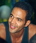 A man with dark hair, wearing a blue tank