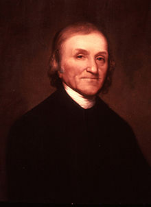 Half-length portrait of an older man. He is wearing a black jacket with the white collar of his shirt showing.