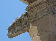 Frise de palmes et de roseaux stylisés alternés, et corniche décorée de moulures « en oves et dards ».