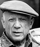 An elderly Pablo Picasso in a cloth cap, grinning at the camera