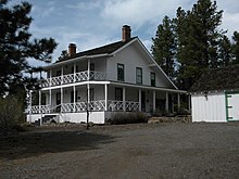 Large rustic white house between trees