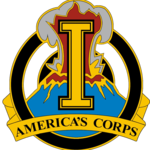 A gold device containing a gold letter I superimposed over an erupting volcano, with the words "America's Corps" at the bottom