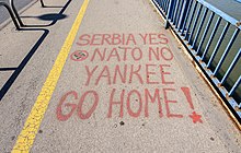 A sidewalk with the words "SERBIA YES NATO NO YANKEE GO HOME!" spray painted in red.