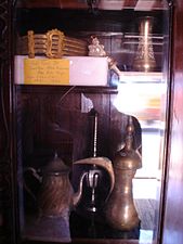 A royal belt and a traditional coffee pot. The design of the coffee pot is influenced by Arab culture.