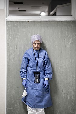 Une femme, debout, baissant la tête, dans un état de totale fatigue.