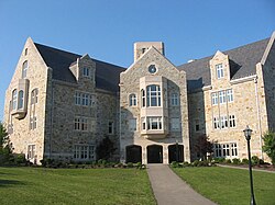 A 4-story stone building, with an asphalt walkway leading to a large entrance area