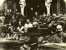 Black-and-white photograph of people sitting at desks