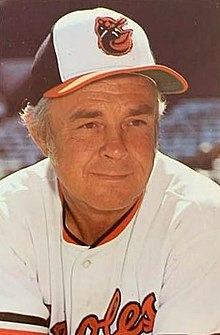 A man in a white baseball jersey and cap