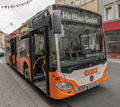 Das Foto zeigt einen Bus, der gerade ohne Fahrer oder Fahrerin ist und auf der Anzeige „HofBus GmbH“ hat. Es zeigt die Zugehörigkeit zum Unternehmen.