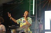 MNEK performing on a stage wearing a multi-coloured shirt.