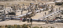 A photograph of Shell Oil's experimental in situ shale oil extraction facility in the Piceance Basin of northwestern Colorado. In the center of the photo, a number of oil recovery pipes lie on the ground. Several oil pumps are visible in the background.
