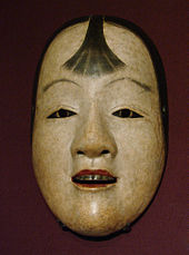 Masque peint en blanc, visage jeune, lèvre rouge et mèche de cheveux sur le font.