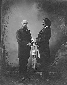 portraits photographiques en pied de Mars (sur la gauche) et Red cloud (sur la droite) se serrant la main. Red Cloud est habillé pour l'occasion à l'européenne, il tient un calumet dans la main gauche.