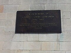 Placa en memoria de Camille Croué-Friedman, exterior de la basílica, sobre el muro de la sacristia, al lado del coro.