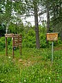 Des panneaux de signalisation de bois avec des inscriptions de lieu et de distance.