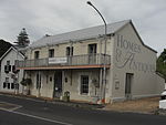 Attached double storey vernacular dwelling; double pitched corrugated iron roof with bargeboards; ashlar plaster decoration to walls; all joinery unpainted. Ground floor: 3-bays; modern stock timber sash windows (12 panes); plaster quoining around window Type of site: Commercial Current use: Offices.