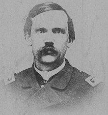 Winslow, aged 34, wearing a military uniform with slicked hair