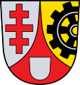 Stadt Neutraubling Durch eine eingeschweifte rote Spitze, darin ein silberner Leerschild, gespalten von Silber und Gold; vorne ein rotes Patriarchenkreuz, hinten ein aus dem Schildrand wachsendes schwarzes Zahnrad.